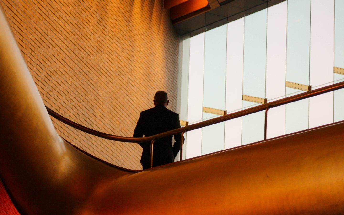 man in stairwell with floor to ceiling glass windows